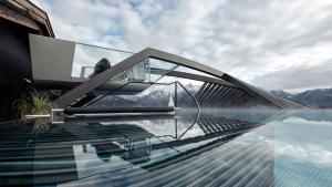 una casa de cristal al borde de un cuerpo de agua en Alps Lodge, en Fiss