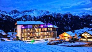 un hôtel dans la neige avec des montagnes en arrière-plan dans l'établissement Alps Lodge, à Fiss