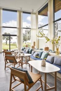 a living room with tables and couches and windows at Empordà Golf Resort in Torroella de Montgrí