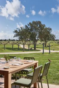 a wooden table with chairs in a field at Empordà Golf Resort in Torroella de Montgrí