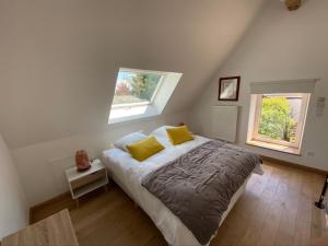um quarto com uma cama com almofadas amarelas e 2 janelas em LA DEMALERIE em Cheverny