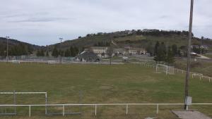 a soccer field with a fence in front of a hill at Appartement tout confort au milieu de la Margeride in Châteauneuf-de-Randon