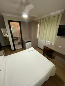 a bedroom with a large white bed and a bathroom at Hotel Esmig in Venda Nova do Imigrante