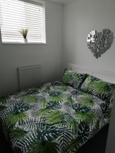 a bedroom with a bed with a green and white comforter at The Antelope Hotel in Merthyr Tydfil