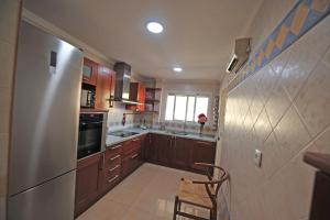 a kitchen with wooden cabinets and a stainless steel refrigerator at Avenida Paseo 3 Rooms 2 baños in Cádiz +16 photos
