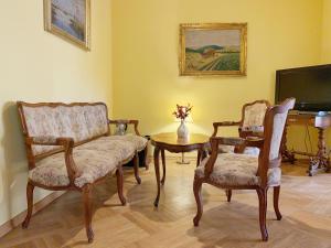 sala de estar con 2 sillas, mesa y TV en Small Luxury Palace Residence en Praga