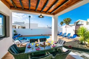 een patio met een tafel en stoelen en een zwembad bij Casa Carra - LH207 By Villas Now Ltd in Playa Blanca