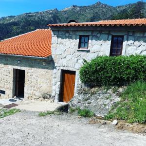 a stone house with an orange door and a mountain at Abrigo das Penhas in Manteigas