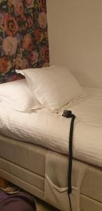 uma cama com lençóis brancos, uma almofada e uma parede floral em Woodstock B & B Studios em Bålsta
