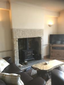a living room with a fireplace and a table at Woodland Cottage in Cowling