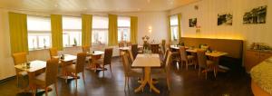 a restaurant with tables and chairs and windows at Lindner's Hotel in Bellheim