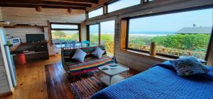 a living room with a bed and a large window at Morros House Pichilemu in Pichilemu