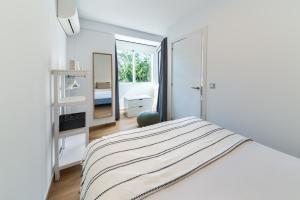 Habitación blanca con cama y espejo en Holidays2Malaga Central Alameda View, en Málaga