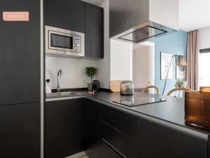 a kitchen with black cabinets and a microwave at limehome Sevilla Calle Torcuato Luca de Tena - Digital Access in Seville