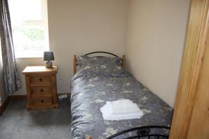 a small bedroom with a bed and a night stand at Woodland Cottage in Cowling