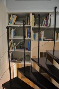 a book shelf filled with books next to a black bench at Le Mas Sivan séjour arlésien 2 à 6 personnes wifi climatisation parking in Arles
