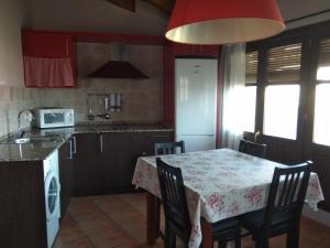 uma cozinha com uma mesa com cadeiras e uma mesa e uma cozinha com um lavatório em casa sampietro 2 em Alquézar