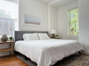 a white bedroom with a large bed and two windows at Historic 1900s Townhome with a Modern Flair in Knoxville