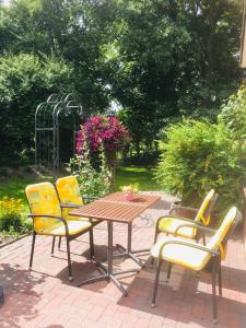 una mesa de madera y 4 sillas amarillas en el patio en Ferienwohnanlage Sturmhöhe en Welt