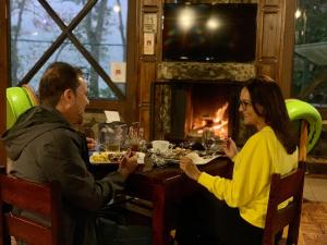 un hombre y una mujer sentados en una mesa comiendo comida en Hotel de Montaña El Pelicano, en San Isidro