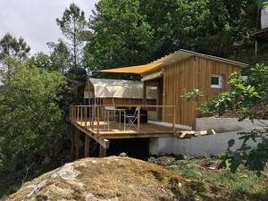 una pequeña casa de madera con terraza en el bosque en Glamping Cabana nas arvores en Ponte da Barca