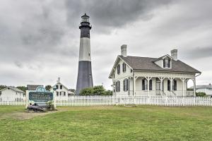 a lighthouse behind a white fence in front of a house at Ideally Located Luxe Beach House on Tybee Island in Tybee Island