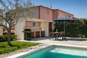 a house with a swimming pool and a table with an umbrella at Belvedere Holidays Villas in Novigrad Istria