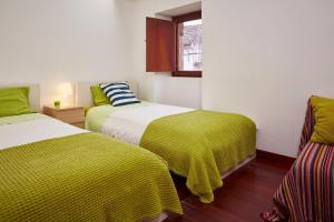 um quarto com duas camas com cobertores amarelos e uma janela em Casa da Pedra Rolada em Janeiro de Cima