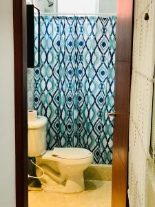 a bathroom with a toilet and a shower curtain at Casa Prada Bed & Breakfast in Bogotá