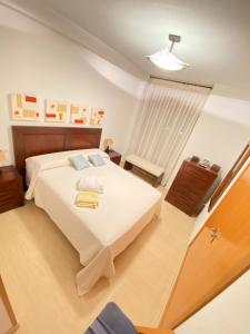 um quarto com uma grande cama branca e uma mesa em S&H La Malasaña em San Vicente del Raspeig