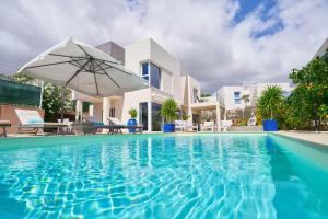 una piscina con sombrilla y una casa en Villa Flamencos Rosas, Costa Adeje, en Playa Paraiso