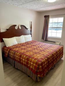 a bedroom with a bed with a plaid blanket and a window at Smoky View Inn in Pigeon Forge