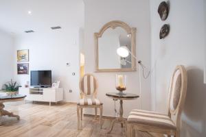 een woonkamer met een tafel, 2 stoelen en een spiegel bij Apartamento Garum in Cádiz