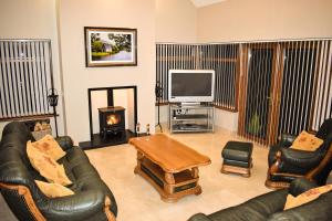 a living room with couches and a tv and a fireplace at Glenshane Country House in Maghera
