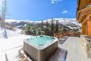 a hot tub on the patio of a house at Chalet Himalaya , 10 Person Chalet with 5 ensuite bedrooms and outdoor jacuzzi in Meribel Centre in Méribel