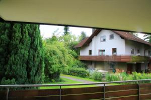 a house with a large tree next to a fence at Immenstaad: Große Ferienwohnung in Immenstaad am Bodensee +1 photo