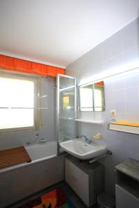 a bathroom with a sink and a tub and a window at Ferienwohnung SEE - ZEIT in Immenstaad am Bodensee