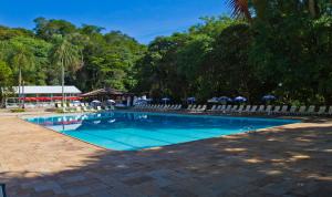 uma piscina com cadeiras e guarda-sóis em Eldorado Atibaia Eco Resort em Atibaia