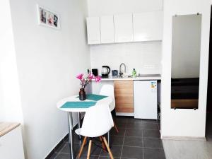 eine kleine Küche mit einem Tisch und weißen Schränken in der Unterkunft Studio Centrum - 1 Maja 16 in Zabrze