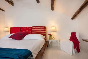 a white bedroom with a bed and a chair at Maison Garibaldi in Cagliari