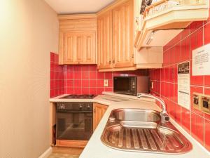 a kitchen with a sink and red tile at Bracken Lodge in Wooler