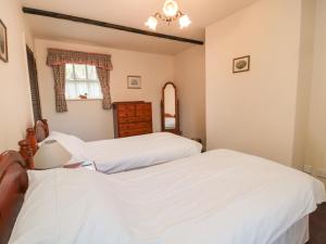 two beds in a bedroom with white sheets at Bracken Lodge in Wooler