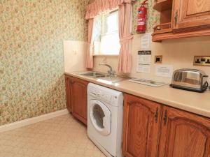 a kitchen with a washing machine and a sink at Blueberry Cottage in Wooler