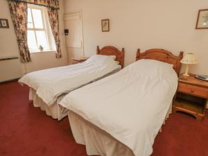 two twin beds in a bedroom with a window at Manor Cottage in Wooler