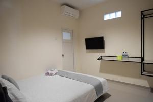 a bedroom with a bed and a tv on the wall at RedDoorz near Ambarrukmo Plaza Mall in Yogyakarta