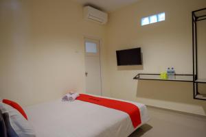 ein Schlafzimmer mit einem Bett und einem Fernseher an der Wand in der Unterkunft RedDoorz near Ambarrukmo Plaza Mall in Yogyakarta + 31 Fotos