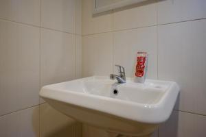 ein weißes Waschbecken in einem weiß gefliesten Bad in der Unterkunft RedDoorz near Ambarrukmo Plaza Mall in Yogyakarta