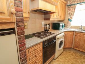 a small kitchen with a stove and a dishwasher at Rose Cottage in Wooler