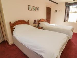 a bedroom with two beds with white sheets and a window at Rose Cottage in Wooler