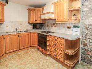 a kitchen with wooden cabinets and a stove top oven at Fern Cottage in Wooler